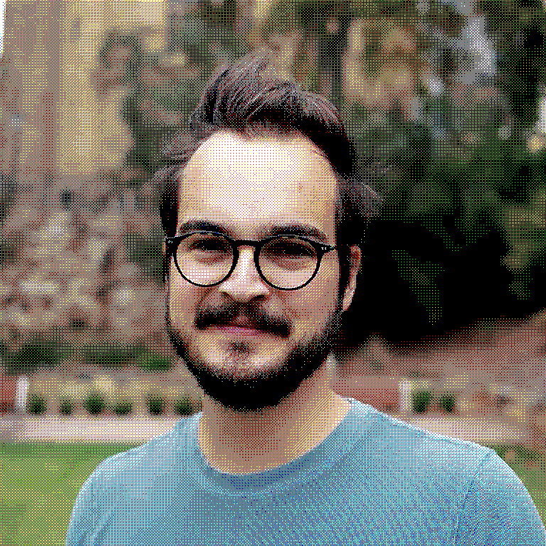 A dithered semi-professional photo of a human head and shoulders, brown hair, glasses, beard, looking toward you with a smile.